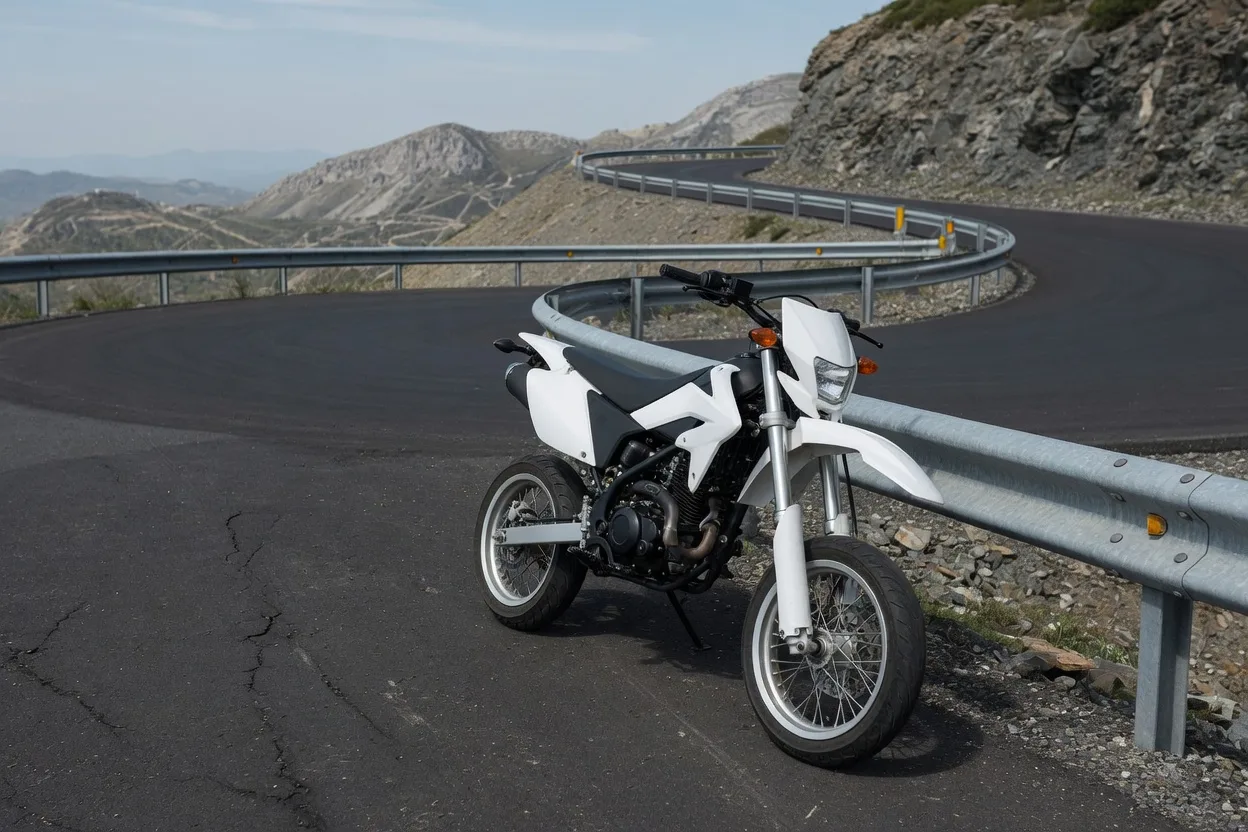 Ilustrační lehký supermoto motocykl v serpentině horské silnice