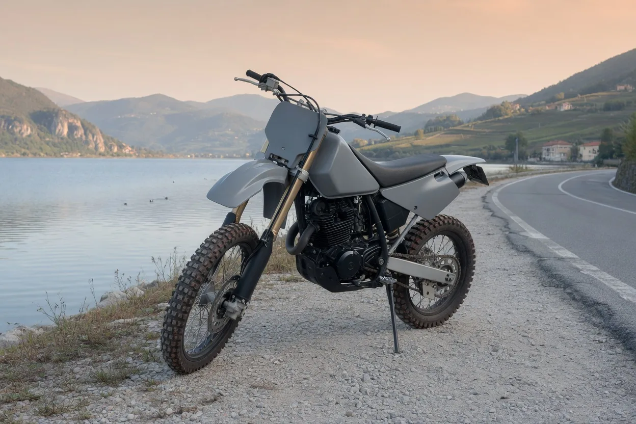 Ilustrační enduro motocykl na štěrkové krajnici u jezera